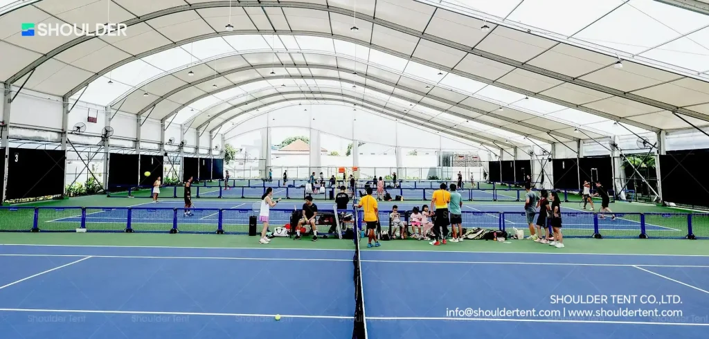 Large-scale aluminum clear span tent providing all-weather protection for tennis.