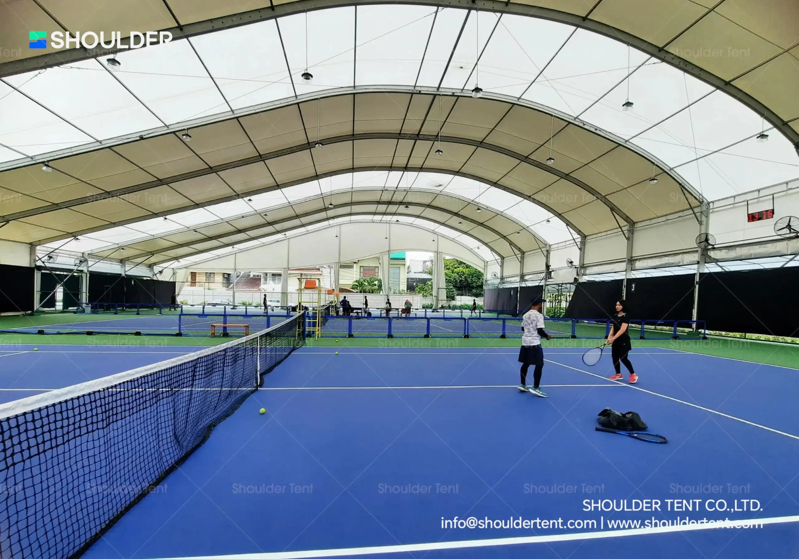 Players on an indoor tennis court built with a heavy-duty aluminum frame.