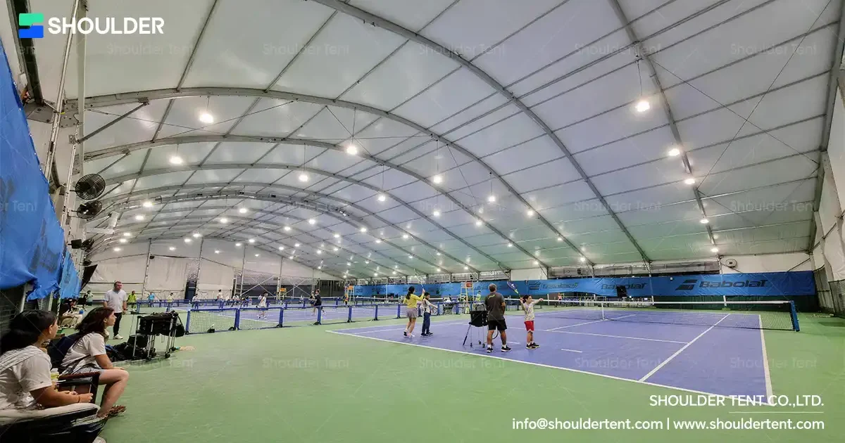 Curved roof aluminum alloy clear span tent sheltering indoor tennis courts.