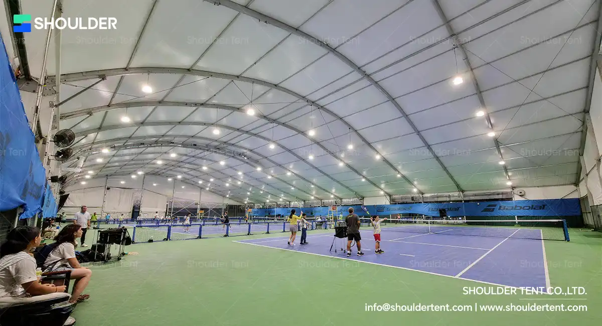 Curved roof aluminum alloy clear span tent sheltering indoor tennis courts.